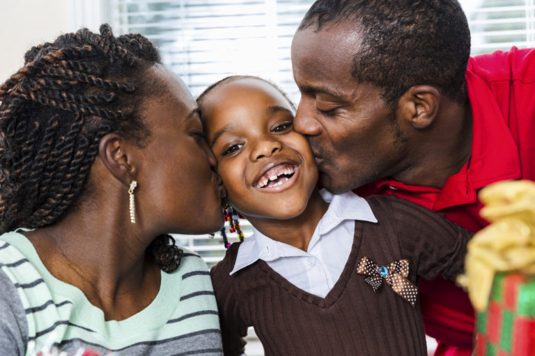 grateful parents kissing toddler